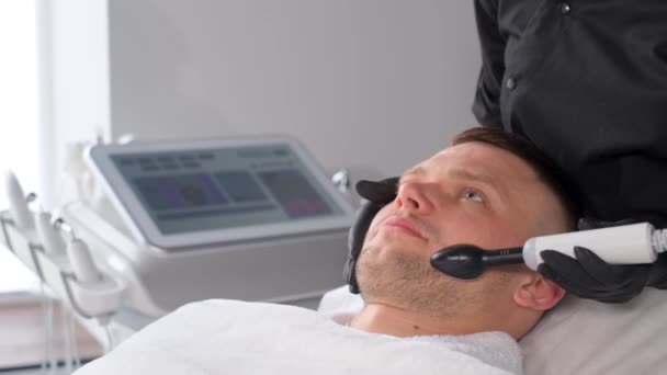 Attraktiv Ung Man Hos Kosmetologen Kosmetolog Utför Ansiktsrullmassage Ung Man — Stockvideo