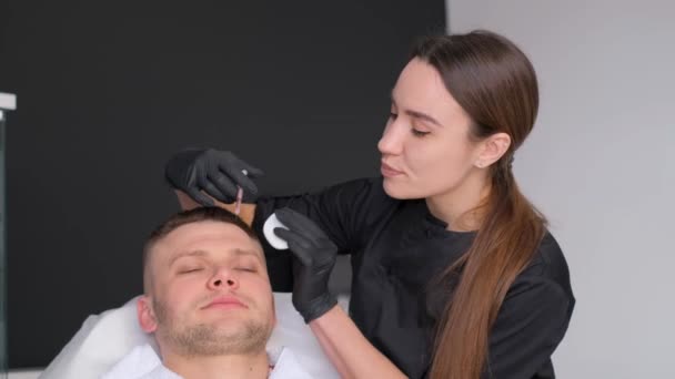 一个年轻英俊男子的肉毒杆菌疗法 一个美容师女孩给一个男人的额头注射了一种年轻化的注射剂 — 图库视频影像