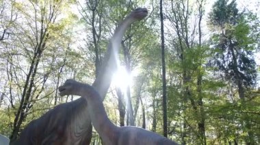 En büyük dinozorlar. Yavrularıyla birlikte bir anne dinozor ormanın ortasında duruyor. Uzun boyunlu bir dinozor. Otçul dinozorlar. Paleontoloji.