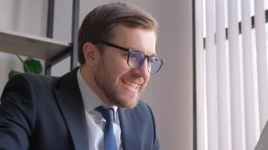 Şaşırmış ve mutlu bir bilişim işçisi. Takım elbiseli bir programcı ofisteki bir bilgisayarda çalışıyor. Başarı duyguları, sevinç