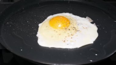 Tavada tavuk yumurtası pişirmek. Baharatlar sahanda yumurtaya düşer. Sıcak, lezzetli kahvaltı, öğle yemeği. Dikey video