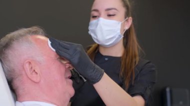 Doktor yaşlı bir adamın yüzündeki kırışıklıklar için botoks yaptırıyor. Modern kozmetoloji kliniği.