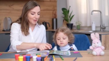 Genç bir anne mutfak masasında otururken kızıyla eğitim oyunları oynar. Küçük çocuk mantık oyunları öğreniyor. 4k video