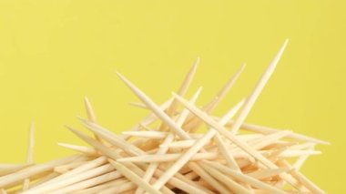 Sarı arka planda dönen bir grup tahta kürdan. Ağız boşluğu ve diğer amaçlar için doğal tahta çubuklar. Dikey video
