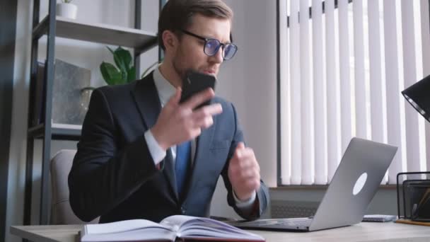 アメリカ出身の忙しい若い投資銀行家が コンピュータで仕事をしている間に電話で話している 忙しいマネージャー オフィスで働く — ストック動画
