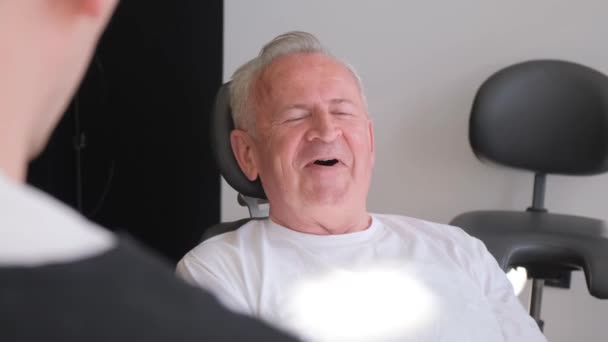 一位年迈的男子正在看牙医 他们正在牙科诊所进行检查时兴高采烈地聊天 垂直录像 — 图库视频影像