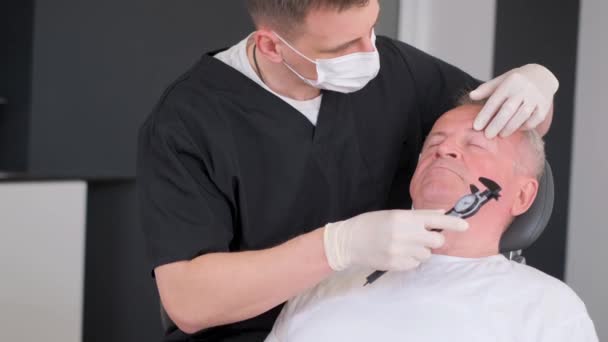 整形外科医は さらに手術のために老人の顔に印を付けます 現代の整形手術 高品質4Kビデオ — ストック動画