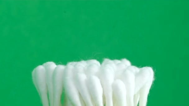 A group of evenly folded ear sticks on a pleasant green background, rotating in a circle. Safe means for ear hygiene. Vertical video