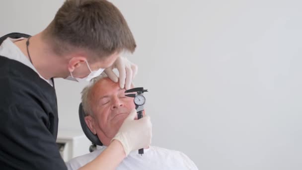 外科医は老人の前にいて 顔に印をつけている 医者は顔にマークを作るために永久的なマーカーを使用し その後 整形手術のためにそれらを準備します — ストック動画