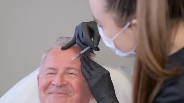 一位老年男子在一位美容师的检查中 坐在现代诊所的椅子上 注射治疗皱纹的疗效观察 — 图库视频影像