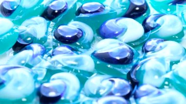 Bir grup mavi çamaşır kapsülünün daireler çizerek döndüğü görüntüyü yakınlaştır. Çamaşır makinesinde yüksek kalitede çamaşır yıkamak için kullanılır. Dikey video