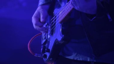 Maskeli bir adam bir kulüpteki rock konserinde elektro bas gitar çalar. Büyük bir şehirde gece hayatı. Kırmızı ve mavi ışık
