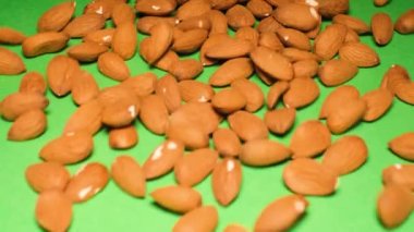 Yeşil arka plana düşen badem fıstıkları. Bademler A ve E vitaminleri bakımından zengindir, bağışıklık sisteminizi korumak için önemlidir.