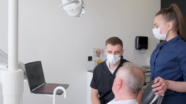 在牙科诊所的检查中 一位老人正在与牙医预约 他们正在愉快地聊天 — 图库视频影像