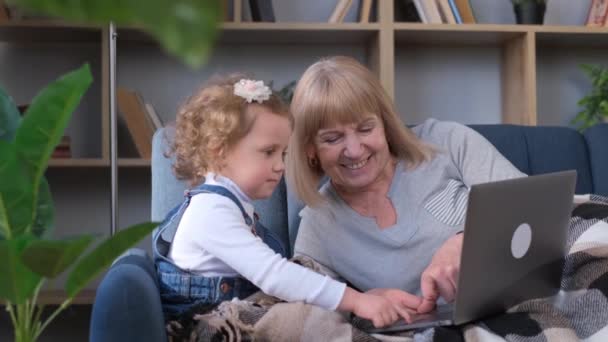 Lycklig Mormor Med Barnbarn Vilar Soffan Hemma Använder Modern Bärbar — Stockvideo