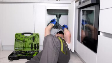 Profesyonel bir tesisatçı mutfak lavabosunu tamir ediyor. Borularda su akışı. Evine bir tesisatçı çağır. Dikey video