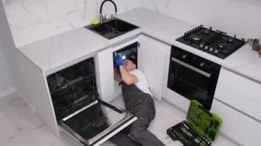 Mutfakta yerde yatan bir tesisatçı lavabo yerleştirir. Tesisatçı işi. Dikey video