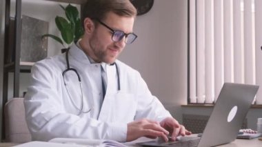 Genç, yakışıklı doktor ofisinde telefonla konuşuyor. Profesyonel bir doktorun tıbbi muayeneleri. Modern tıbbi bakım. Dikey video