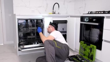 Bulaşık makinelerinin tamiri. Efendi eve geldi ve bulaşık makinesini tamir ediyor. Dikey video