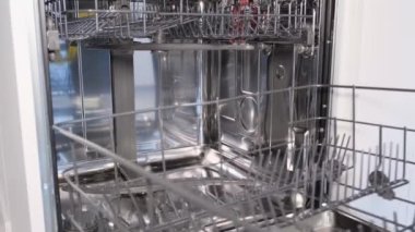 İşten sonra boş bulaşık makinesi. Lastik eldivenli bir adam bulaşık makinesinin kapısını kapatıyor..