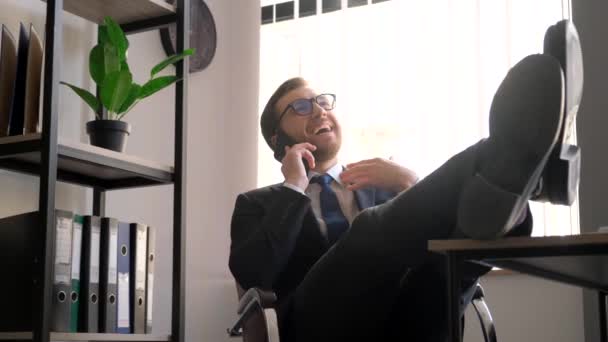 Happy Businessman Workplace Has Put His Feet Table Talking Smartphone — стоковое видео
