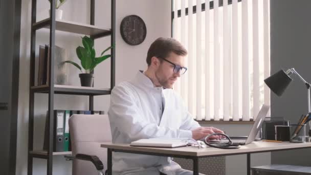 Serieuze Dokter Glazen Werkend Een Laptop Zittend Aan Een Tafel — Stockvideo