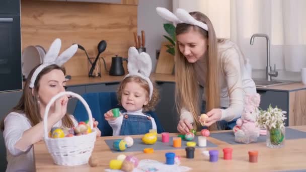 幸せな家族はイースターのために卵をペイントし 彼らはウサギの耳に身を包んだ イースター休暇のコンセプト 4Kビデオ — ストック動画