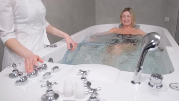 Eine Masseurin Massiert Ein Mädchen Einer Badewanne Mit Einem Wasserstrahl — Stockvideo