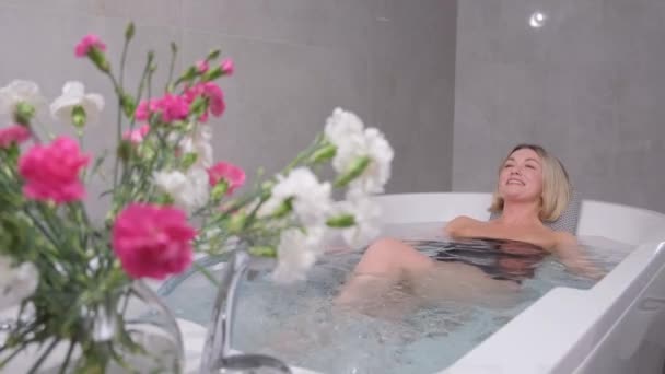 穿着泳衣的年轻女子坐在豪华温泉浴池里放松 快乐的女人洗澡 在美容中心放松水疗 — 图库视频影像