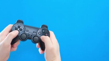 Genç bir adam mavi ekran arka planında joystick ile oynar. Mavi kromakey. Bilgisayar oynatıcı