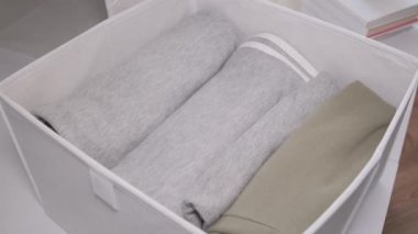 Tekstil çantası ve katlanmış elbiseli bir organizatör. Düzen ve depolama kavramı. Dikey depolama yöntemi. Yukarıdan görüntüle.