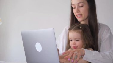 Anne ve küçük kızı evdeki bilgisayarda uzaktan çalışıyor. Çocuk ağIıyor. İş kadını evde çalışıyor.