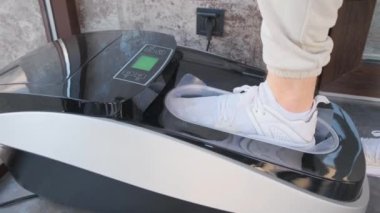 Otomatik olarak ayakkabı kılıfı takan, spor ayakkabılı bir adam ayakkabı kılıfı takan, elektronik bir tokmak takan bir cihaz. 4k video