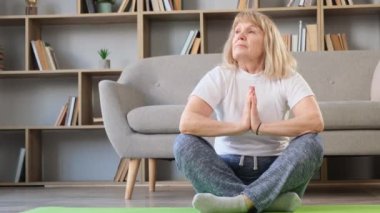 Yaşlı, sarışın bir kadın yoga yapıyor. Kendinle uyum içinde. Kendine zaman ayır.