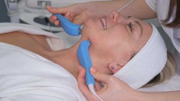 病人接受电动面部按摩 皮肤年轻化和皱纹平滑 微电流疗法 垂直录像 — 图库视频影像