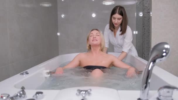リラックスした女性は スパセンターのプロの美容師からハイドロマッサージを受ける 水の手順の助けを借りて背中の治療 バーティカルビデオ — ストック動画