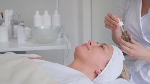 Kosmetyczka Stosująca Serum Kosmetyczne Kobiecą Twarz Centrum Kosmetologii Pielęgnacja Twarzy — Wideo stockowe