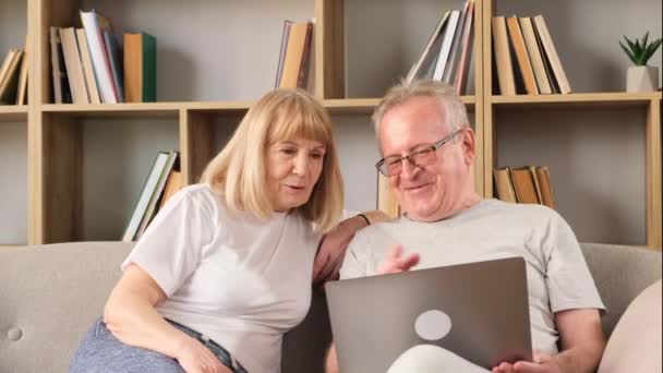 Ευτυχισμένο Ζευγάρι Ηλικιωμένων Που Κάθονται Στο Σαλόνι Και Κοιτάζουν Λάπτοπ — Αρχείο Βίντεο