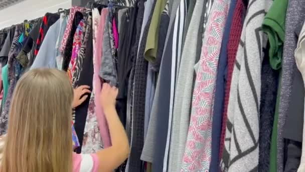 Seorang Wanita Muda Memilih Pakaian Toko Jumat Hitam Pakaian Bekas — Stok Video