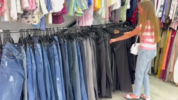若い女性がセカンドハンドを買う 店内で使用する服 — ストック動画