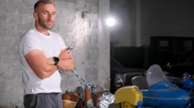 Motosikletin yanındaki garajda profesyonel bir tamircinin portresi. Motosiklet servisi.
