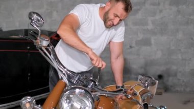 Bir tamirci bir benzin istasyonunda bir motosiklet tamir eder. Güzel motosiklet. Dikey video.