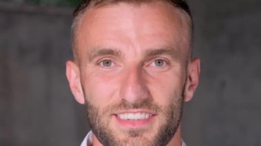 Close-up portrait of a handsome brutal man with a beard looking at the camera and smiling. Happy person