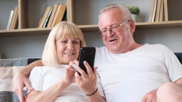 Grandfather Grandmother Sitting Home Sofa Watching Entertainment Programs Smartphone Smiling — стоковое видео