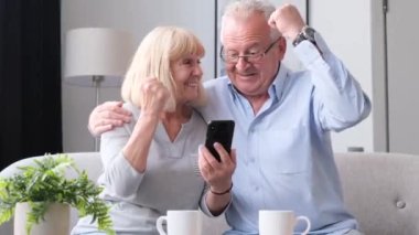 Grandparents hit the jackpot in a mobile app. Gambling games, casino in smartphone.