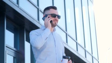 The director makes a phone call while standing by the glass office. Confident bearded executive manager having a phone conversation on the phone