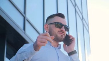 Angry businessman arguing talking on smartphone. A man shouted while talking on the phone while standing outside a business center