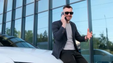 Young handsome man on the street near the office center talking on the phone. Businessman is working.