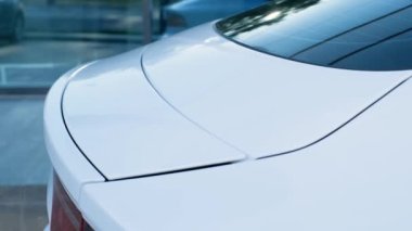 Close-up of the rear spoiler of a white sports car.