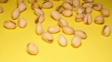 Macro, pistachios falling on a yellow background in slow motion. Super slow motion.